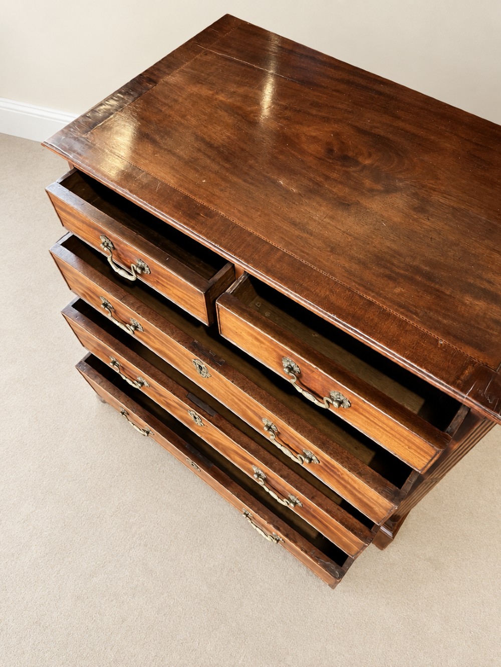 An antique George III mahogany chest of drawers featuring two short over three long drawers with decorative brass swan-neck handles and bracket feet. View VII