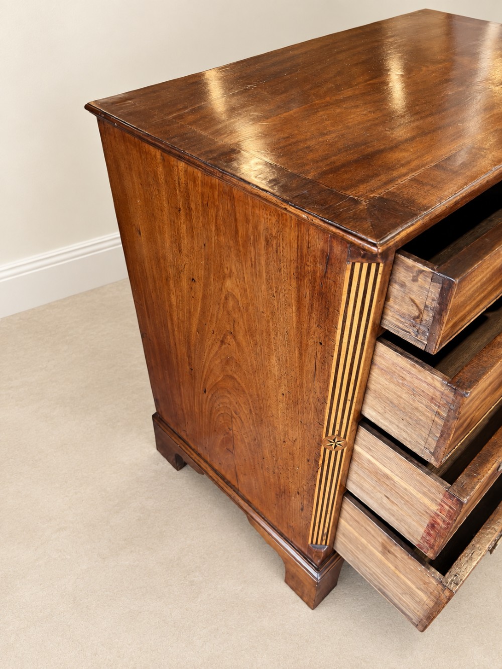 An antique George III mahogany chest of drawers featuring two short over three long drawers with decorative brass swan-neck handles and bracket feet. View X