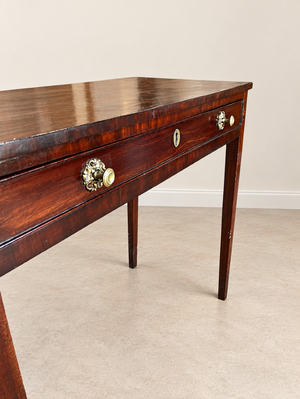 An antique nineteenth-century mahogany side table featuring a single drawer, brass handles, decorative oval floral inlay, and slender tapered legs. View VII