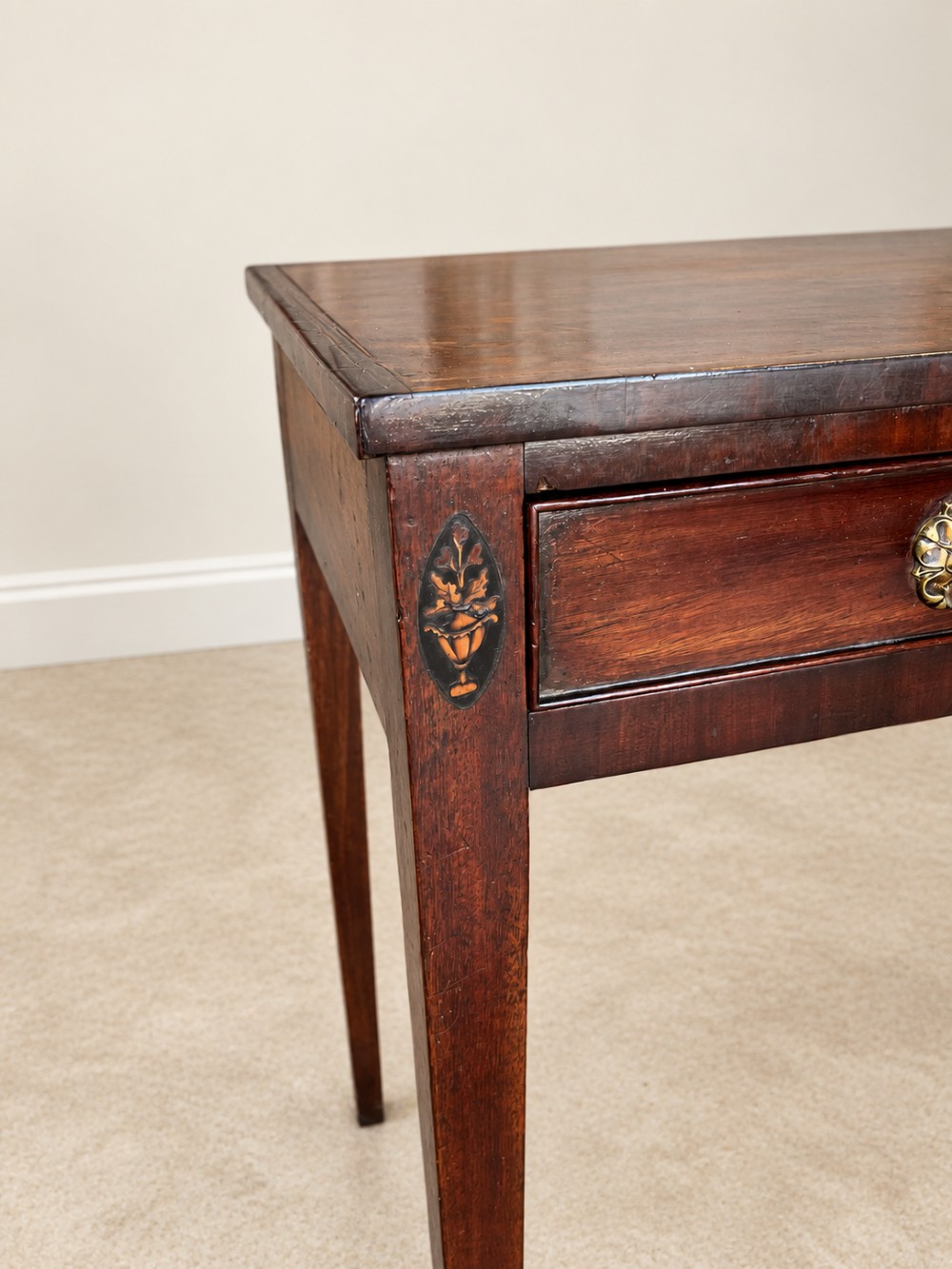 An antique nineteenth-century mahogany side table featuring a single drawer, brass handles, decorative oval floral inlay, and slender tapered legs. View VIII