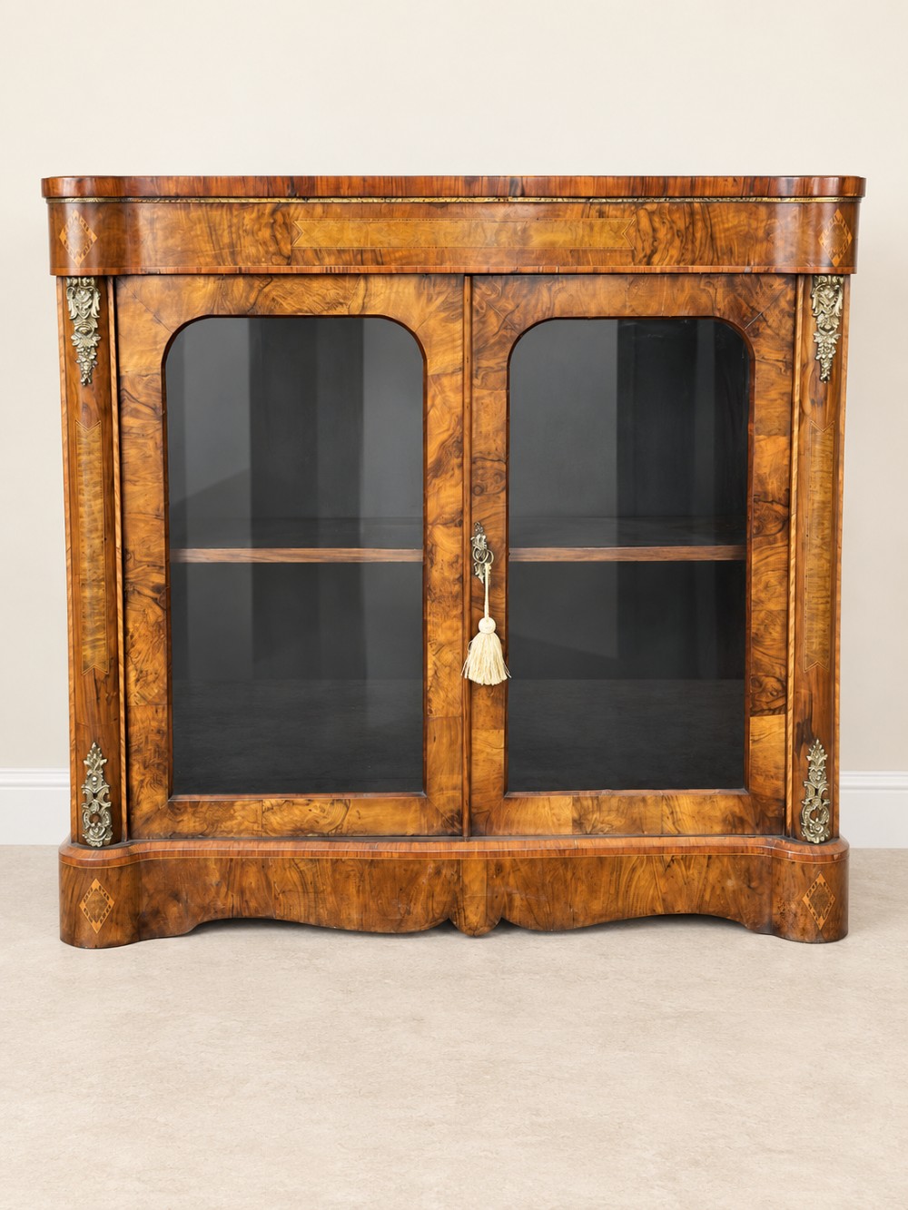 A 19th-century burr walnut low bookcase featuring two glazed doors, a serpentine front profile, geometric marquetry inlay, and decorative brass mounts. View II