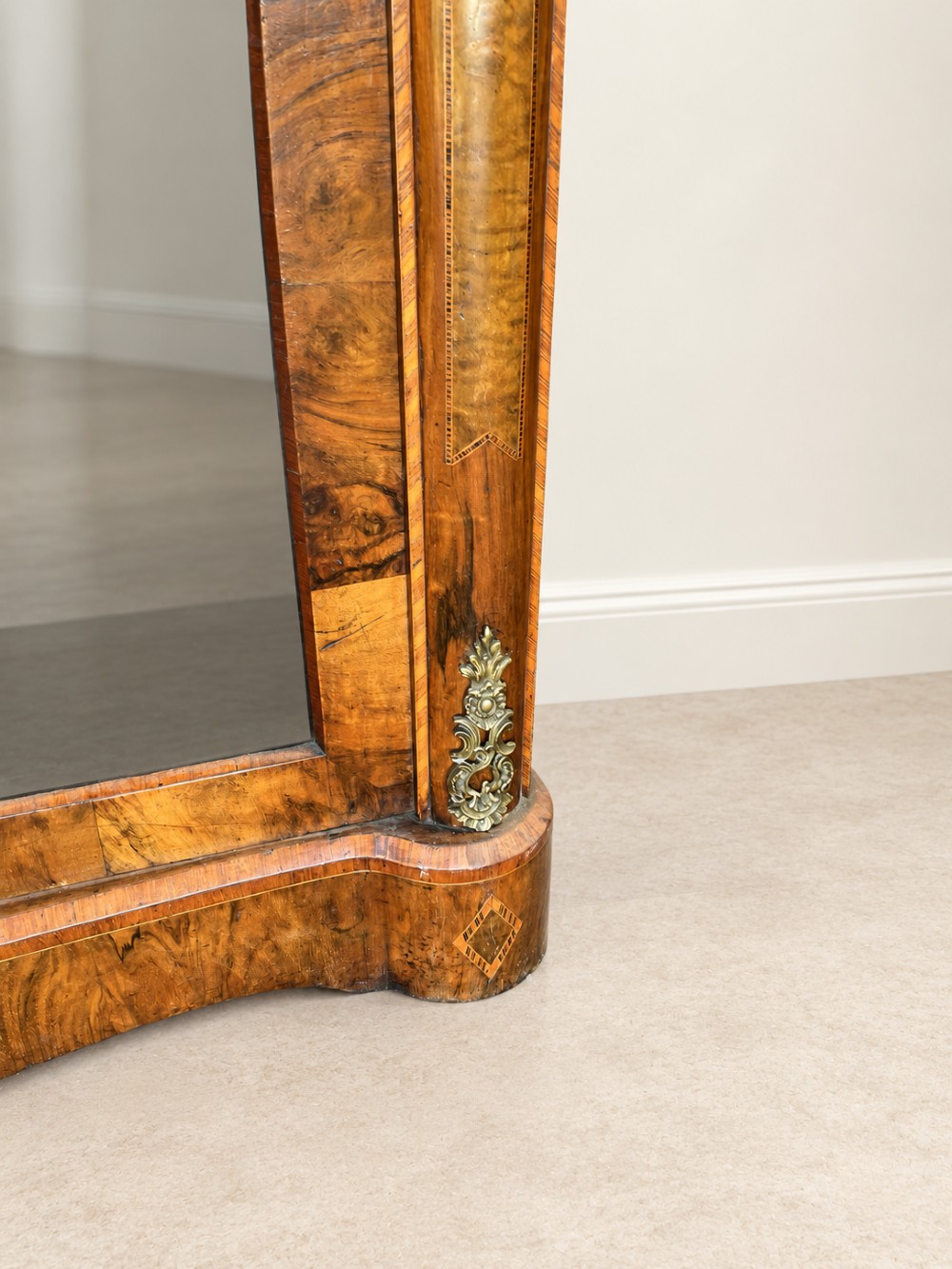 A 19th-century burr walnut low bookcase featuring two glazed doors, a serpentine front profile, geometric marquetry inlay, and decorative brass mounts. View V