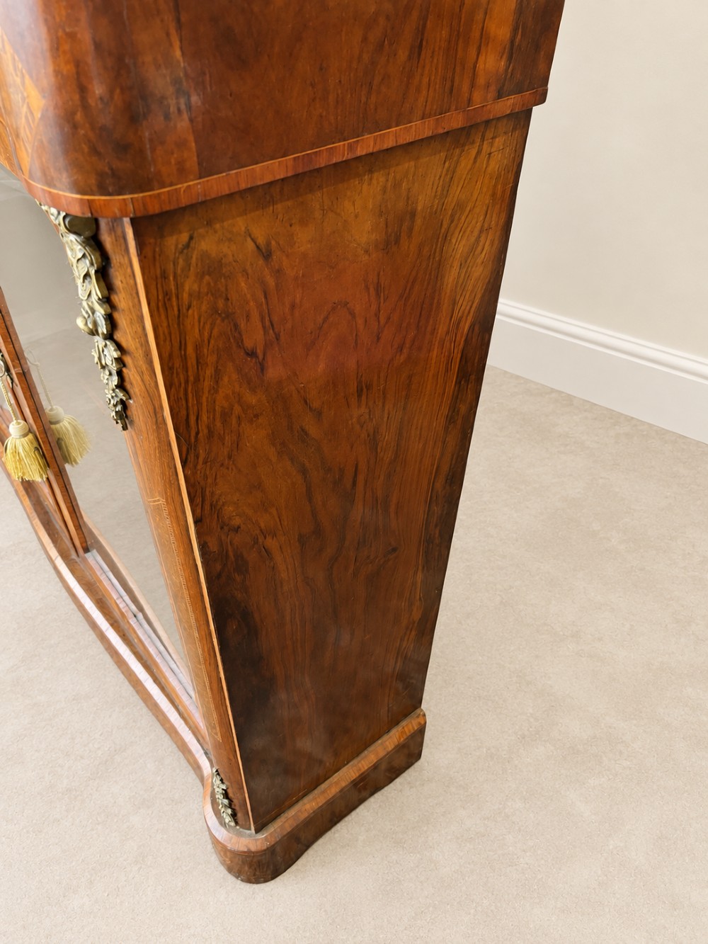 A 19th-century burr walnut low bookcase featuring two glazed doors, a serpentine front profile, geometric marquetry inlay, and decorative brass mounts. View VII