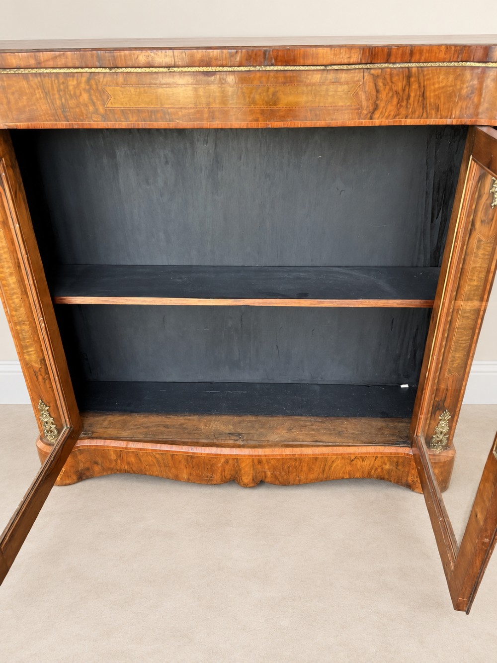 A 19th-century burr walnut low bookcase featuring two glazed doors, a serpentine front profile, geometric marquetry inlay, and decorative brass mounts. View VIII