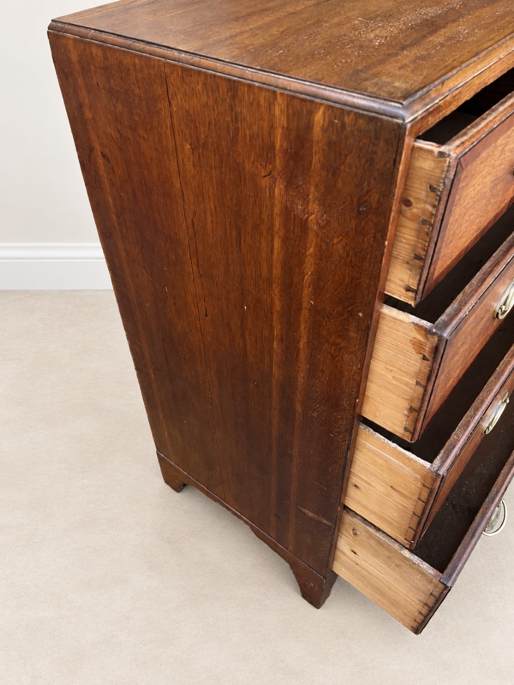 An antique Georgian oak chest of drawers featuring two short drawers above three long drawers with oval brass handles and bracket feet. View VIII