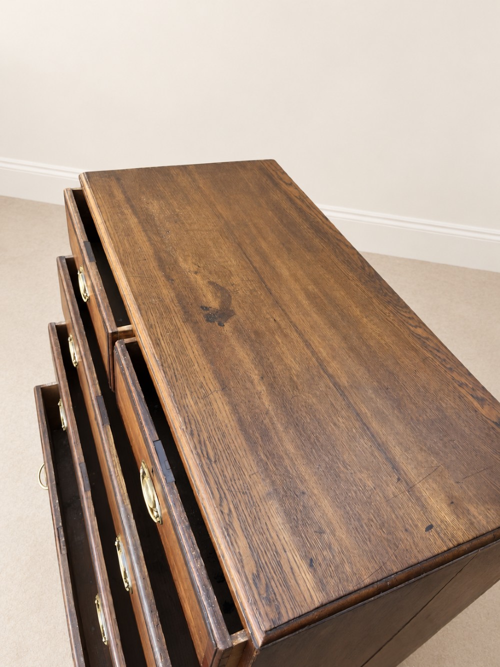 An antique Georgian oak chest of drawers featuring two short drawers above three long drawers with oval brass handles and bracket feet. View IX