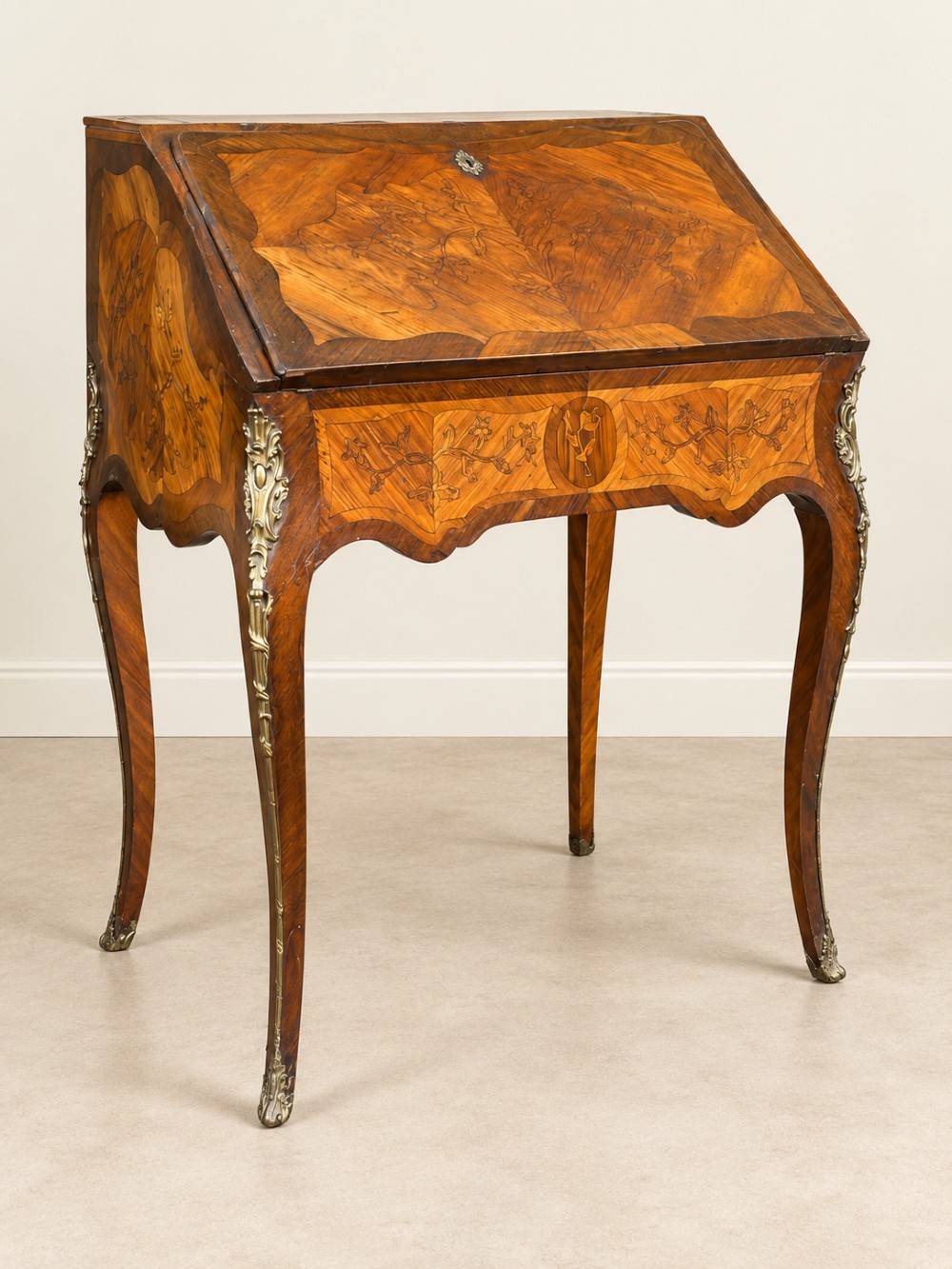 An antique French style slant-front writing bureau featuring floral marquetry inlay, slender cabriole legs, and decorative metal mounts.