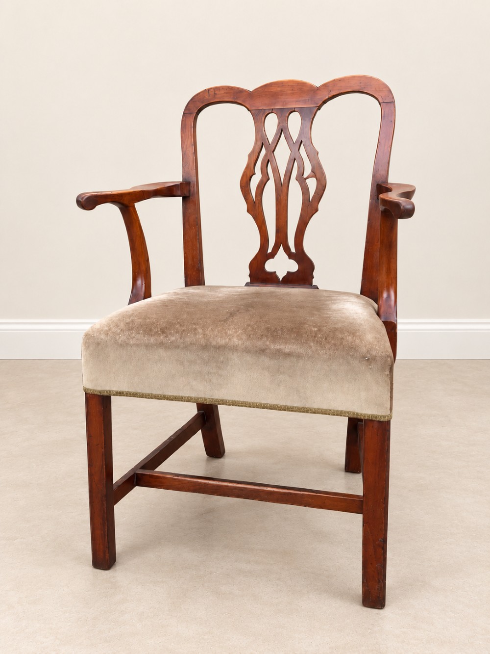 A Georgian yew wood armchair featuring a pierced back splat, curved arms, square legs with stretchers, and a neutral velvet upholstered seat.