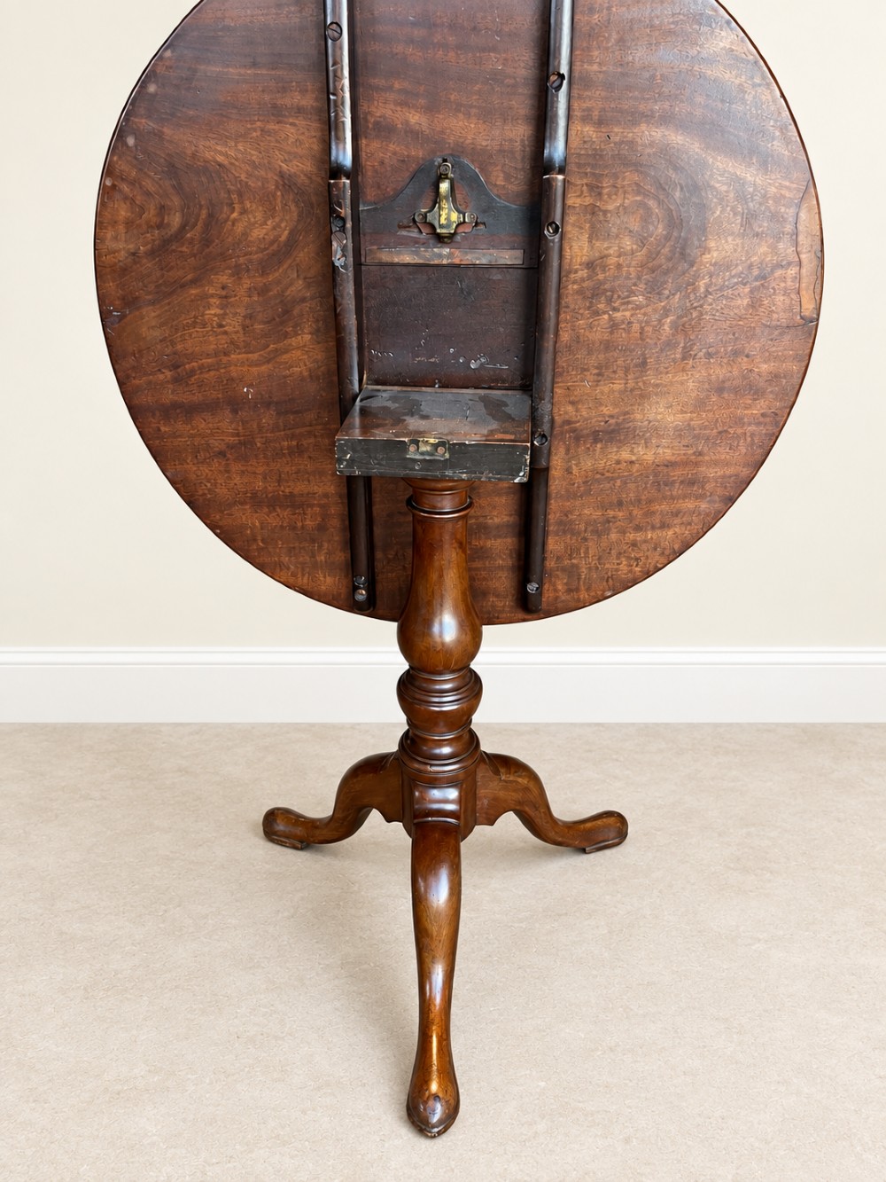 An 18th-century Georgian mahogany tilt-top table shown with its circular top locked vertically above a turned pedestal base with three cabriole legs. View IV