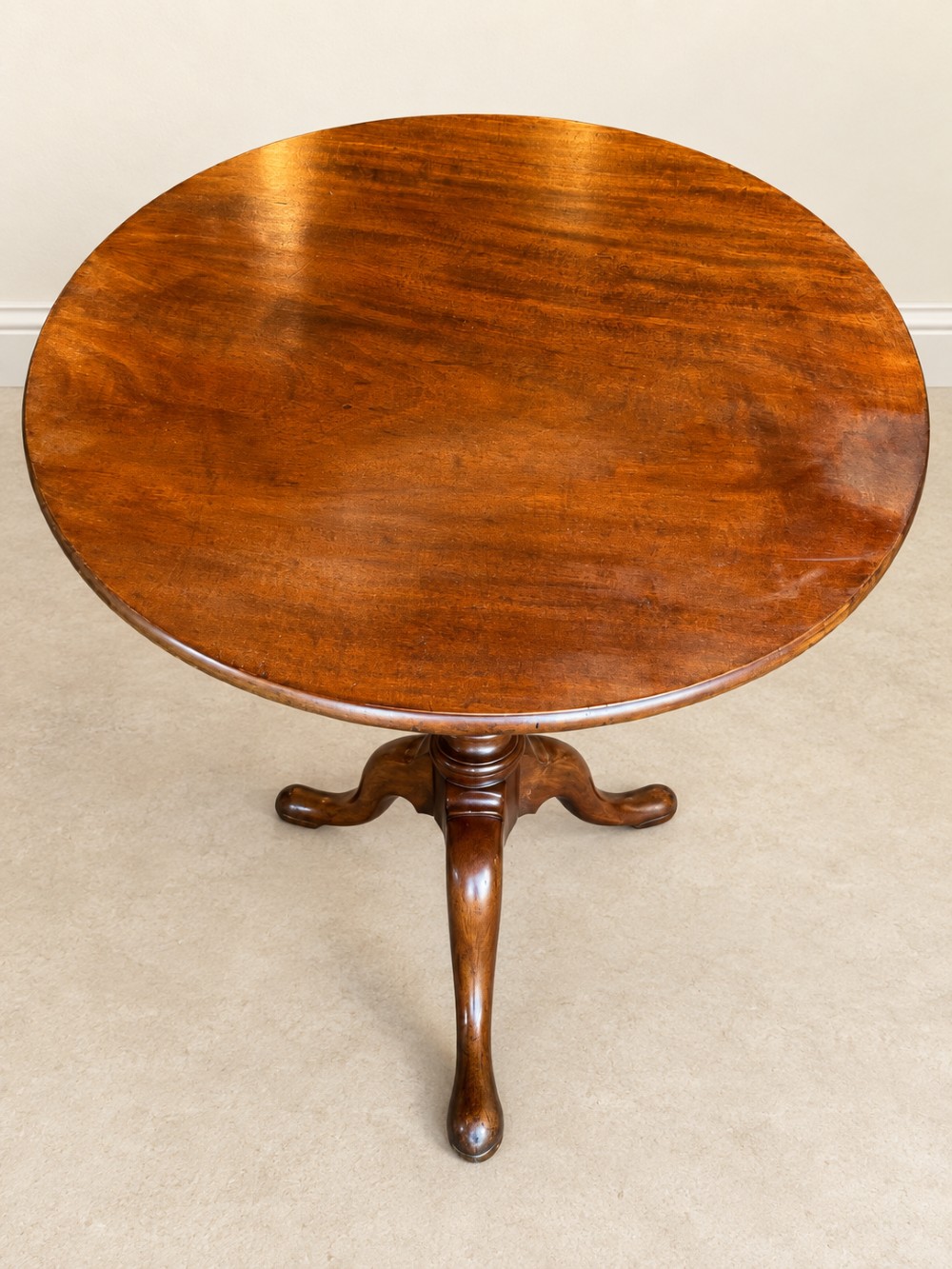 An 18th-century Georgian mahogany tilt-top table shown with its circular top locked vertically above a turned pedestal base with three cabriole legs. View VI
