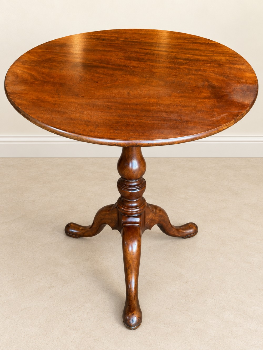 An 18th-century Georgian mahogany tilt-top table shown with its circular top locked vertically above a turned pedestal base with three cabriole legs. View VIII