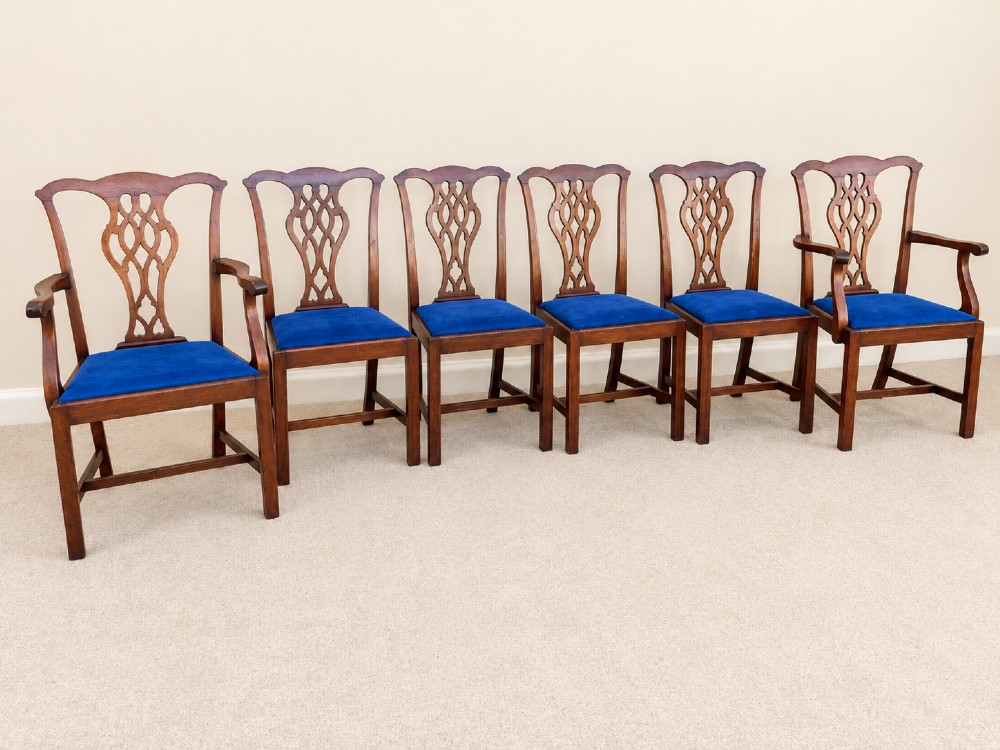 A set of six mahogany Chippendale style dining chairs comprising two carver armchairs and four side chairs with pierced fretwork backs and blue fabric drop-in seats.