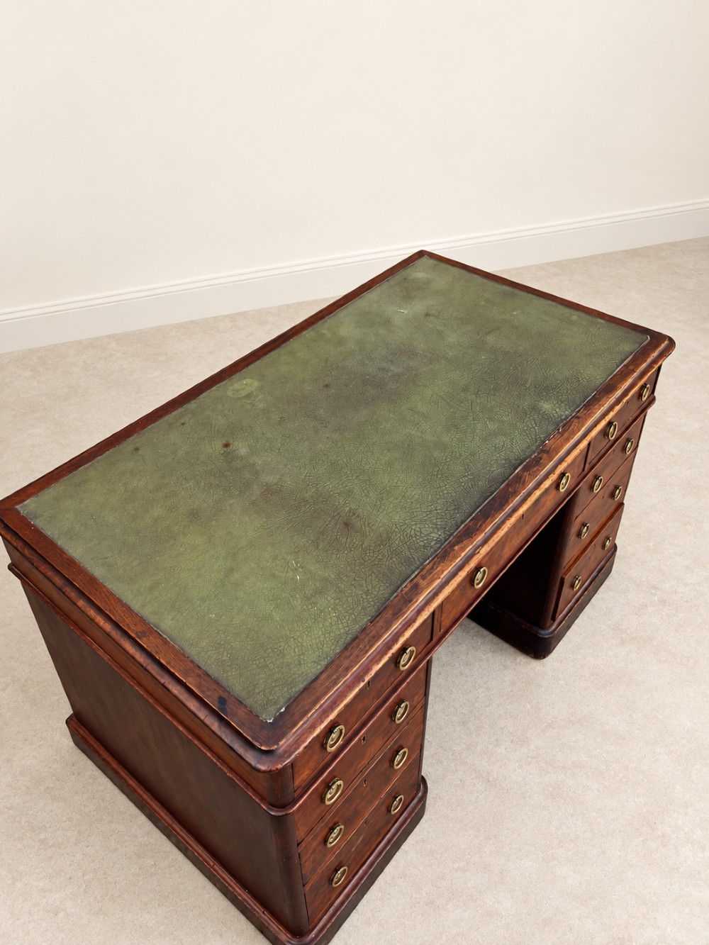 A 19th-century dark mahogany pedestal desk featuring nine drawers with brass handles and an inset green leather writing surface. View IV