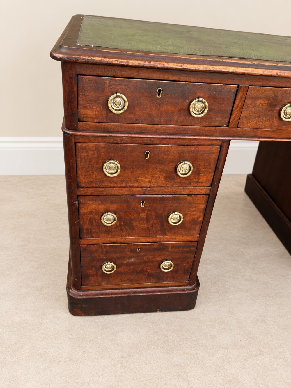A 19th-century dark mahogany pedestal desk featuring nine drawers with brass handles and an inset green leather writing surface. View V