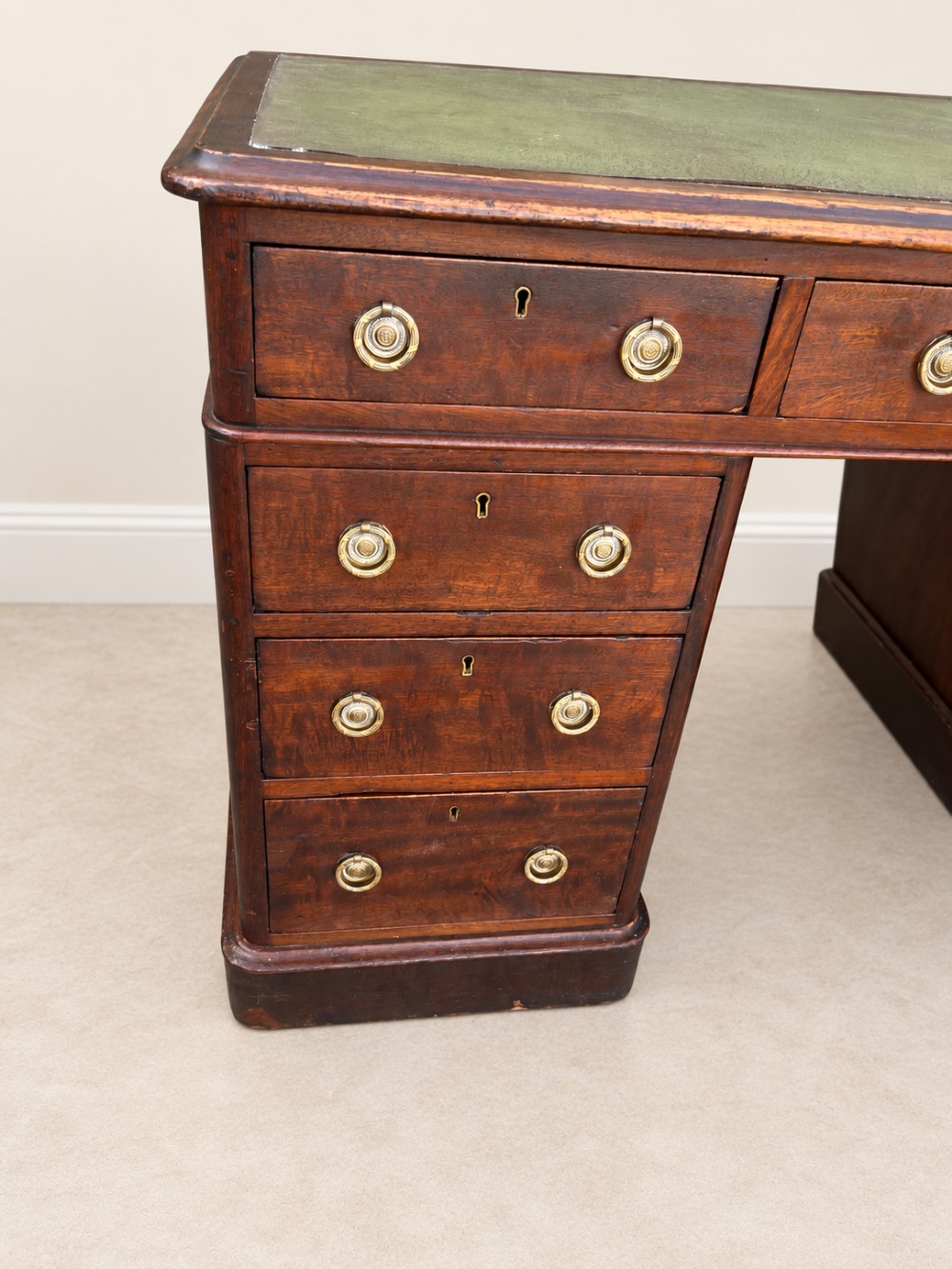 A 19th-century dark mahogany pedestal desk featuring nine drawers with brass handles and an inset green leather writing surface. View VI