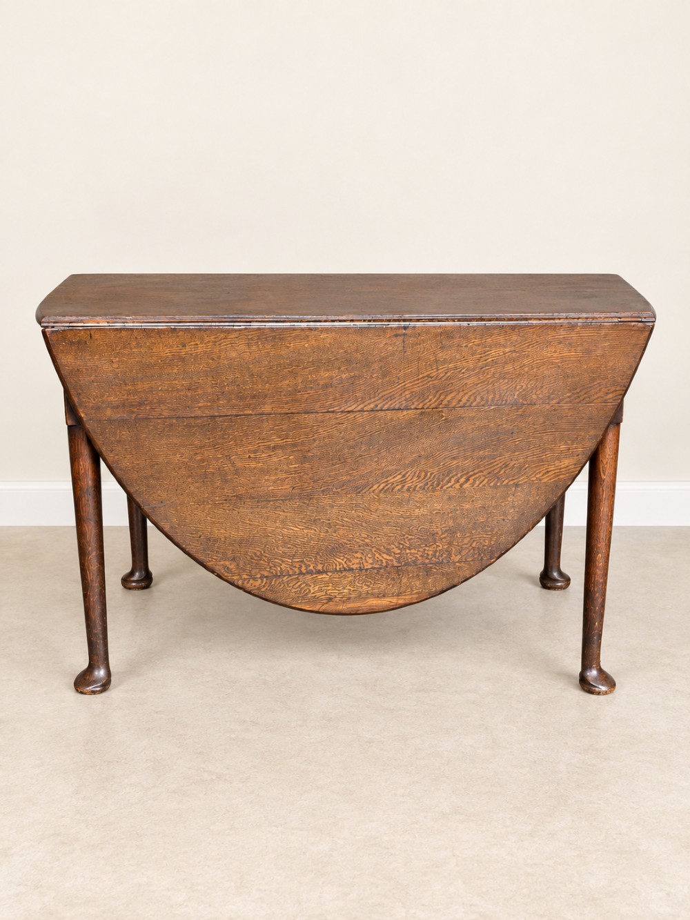 An antique Georgian dark oak drop-leaf dining table featuring an oval tabletop supported by gatelegs and pad feet. View III