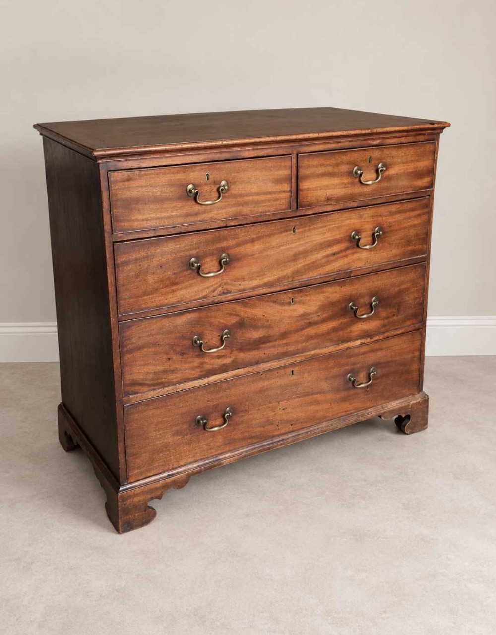 An antique Georgian mahogany chest of drawers featuring a two-over-three drawer configuration, brass swan-neck handles, escutcheons, and bracket feet. View VI