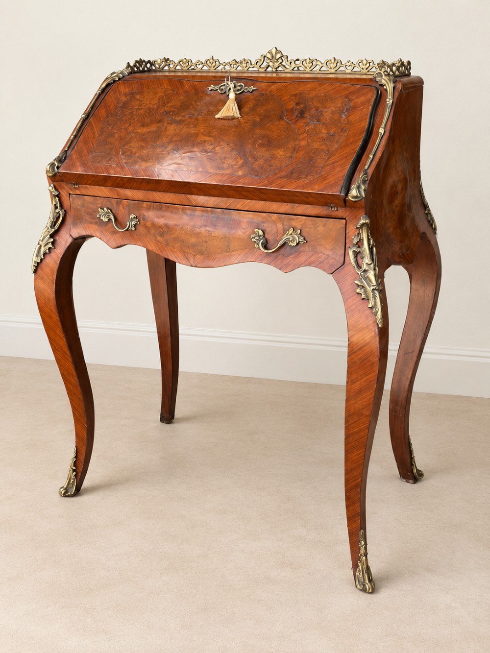 A 19th-century French Louis XV style walnut slant-front writing bureau featuring marquetry veneer, ornate gilt-bronze mounts, a brass pierced gallery, and long cabriole legs.