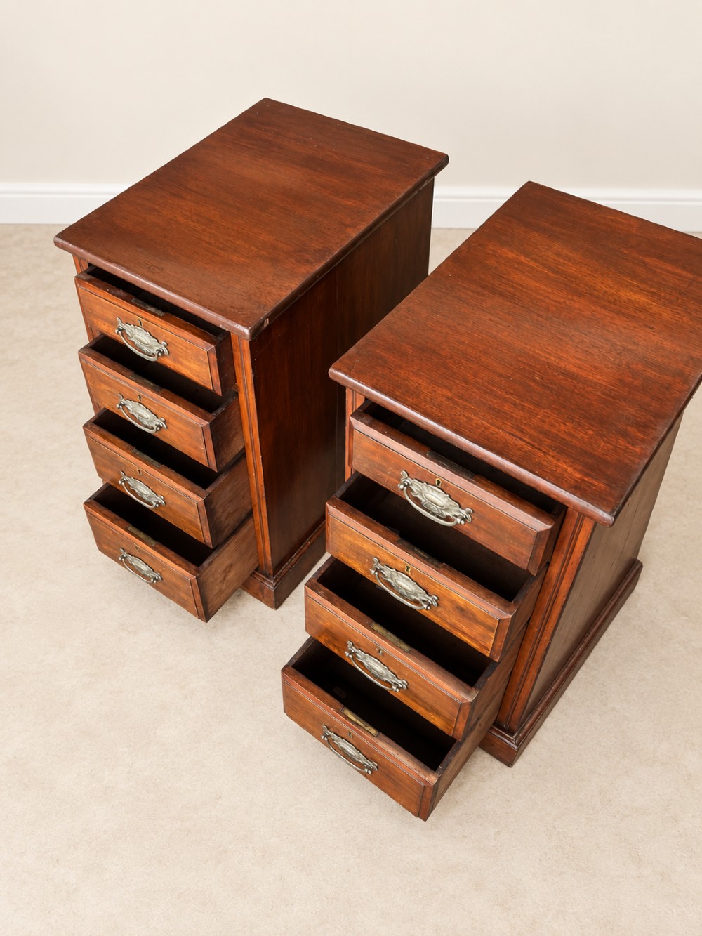 A pair of late Victorian mahogany bedside chests, each featuring four drawers with metal swing handles and a solid plinth base. View V