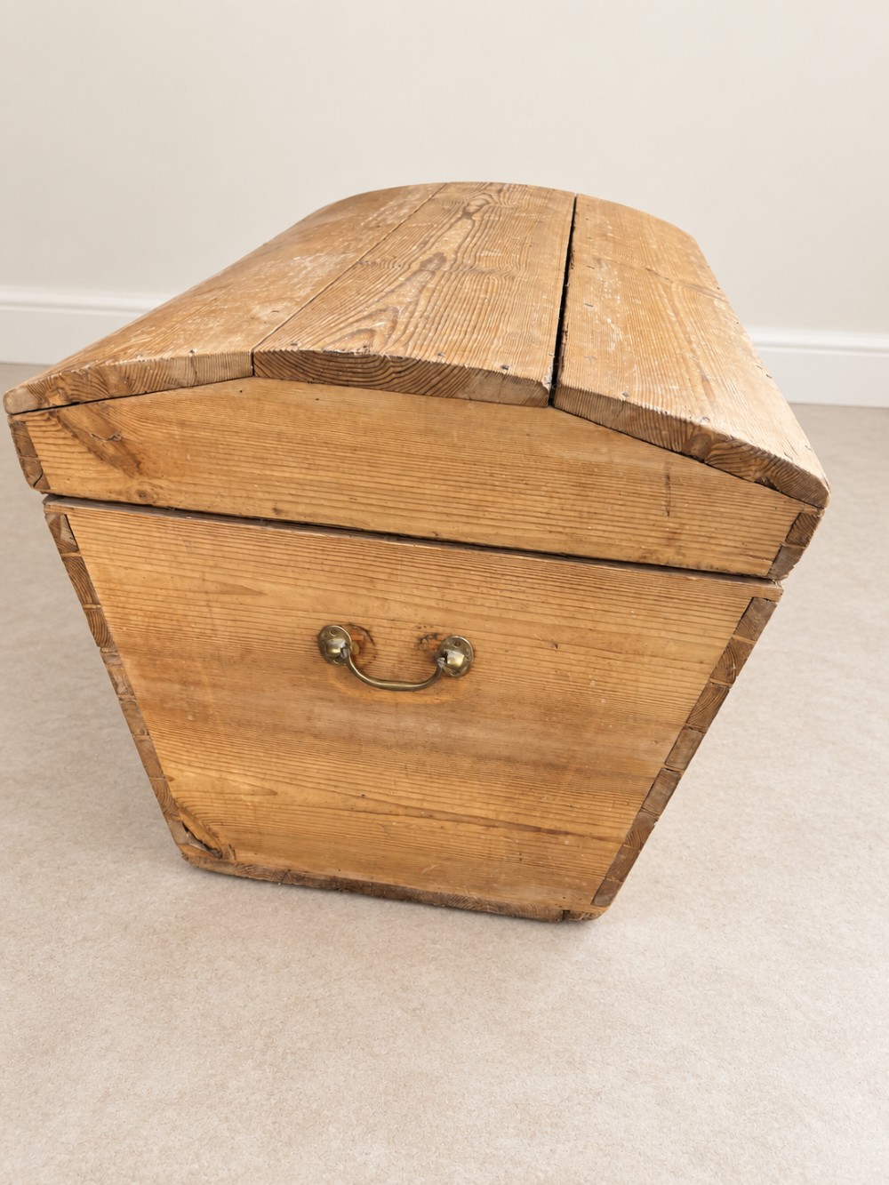 A nineteenth-century pine trunk featuring a curved lid, visible dovetail corner joints, a brass keyhole escutcheon, and brass side handles. View II