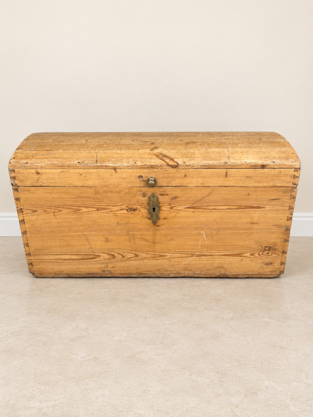 A nineteenth-century pine trunk featuring a curved lid, visible dovetail corner joints, a brass keyhole escutcheon, and brass side handles. View III
