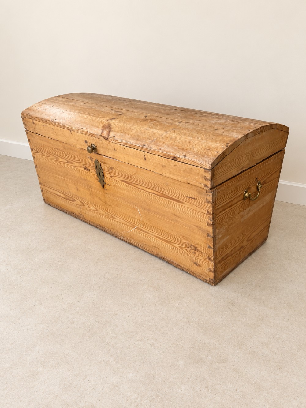 A nineteenth-century pine trunk featuring a curved lid, visible dovetail corner joints, a brass keyhole escutcheon, and brass side handles. View IV