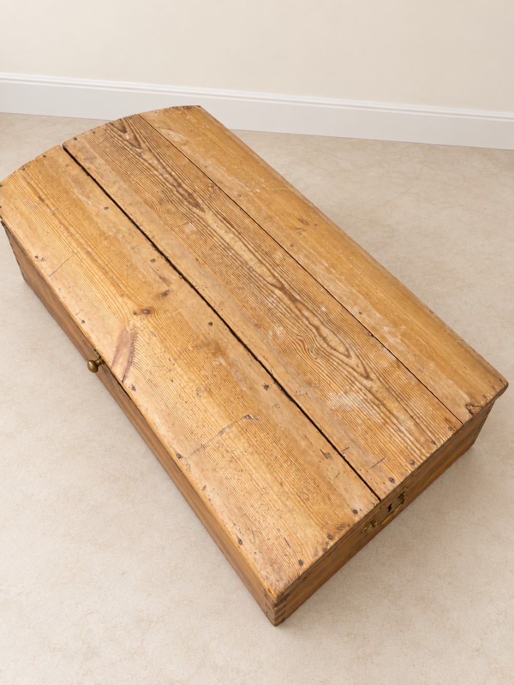 A nineteenth-century pine trunk featuring a curved lid, visible dovetail corner joints, a brass keyhole escutcheon, and brass side handles. View V