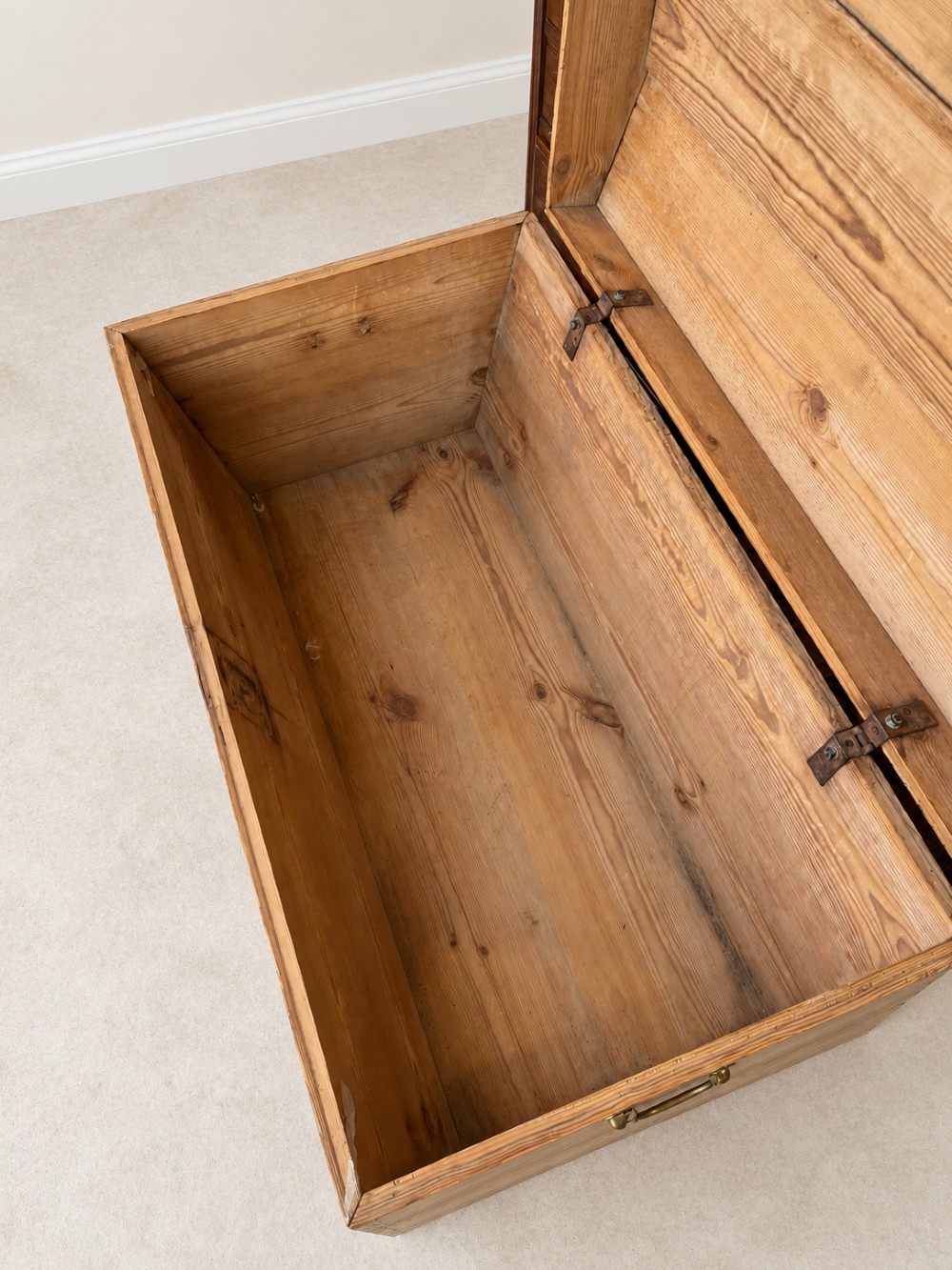 A nineteenth-century pine trunk featuring a curved lid, visible dovetail corner joints, a brass keyhole escutcheon, and brass side handles. View VI