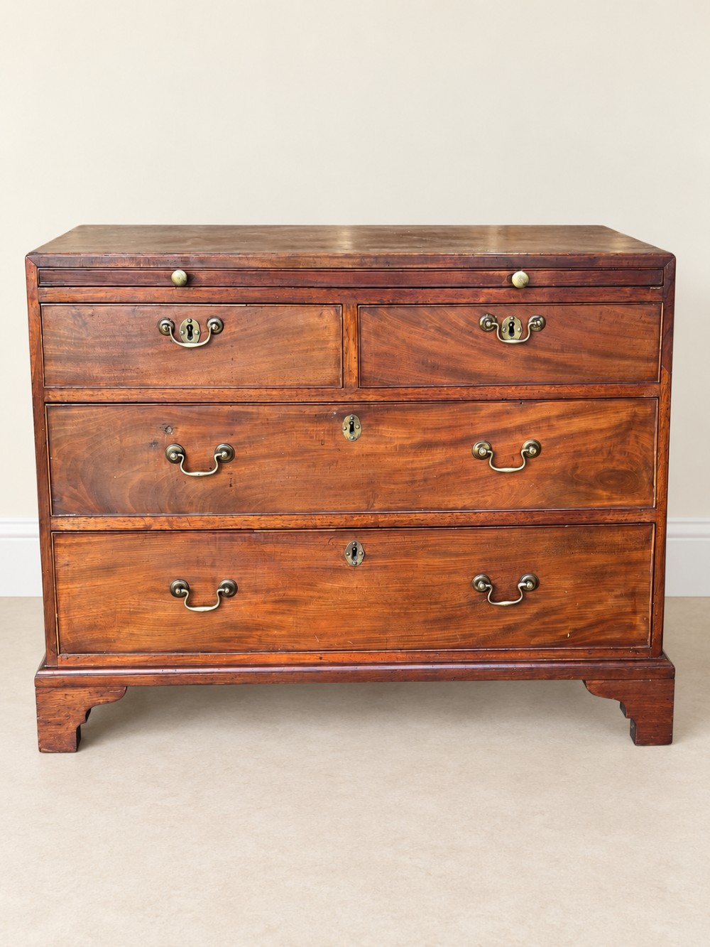 A Georgian mahogany bachelors chest featuring a brushing slide, two short over two long drawers, brass swan-neck handles, and bracket feet. View III