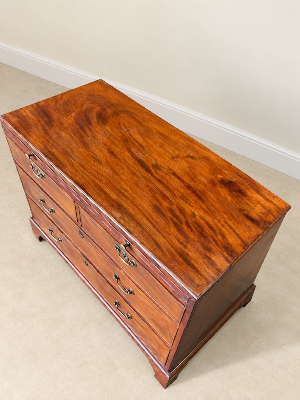 A Georgian mahogany bachelors chest featuring a brushing slide, two short over two long drawers, brass swan-neck handles, and bracket feet. View IV