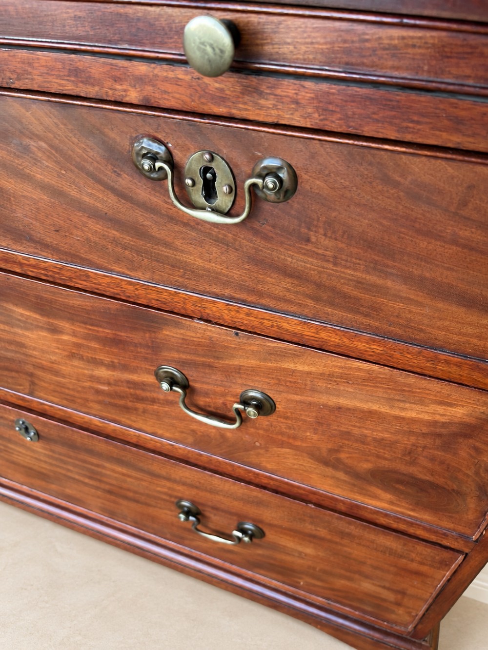 A Georgian mahogany bachelors chest featuring a brushing slide, two short over two long drawers, brass swan-neck handles, and bracket feet. View VII