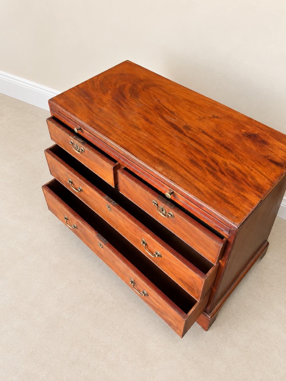 A Georgian mahogany bachelors chest featuring a brushing slide, two short over two long drawers, brass swan-neck handles, and bracket feet. View IX