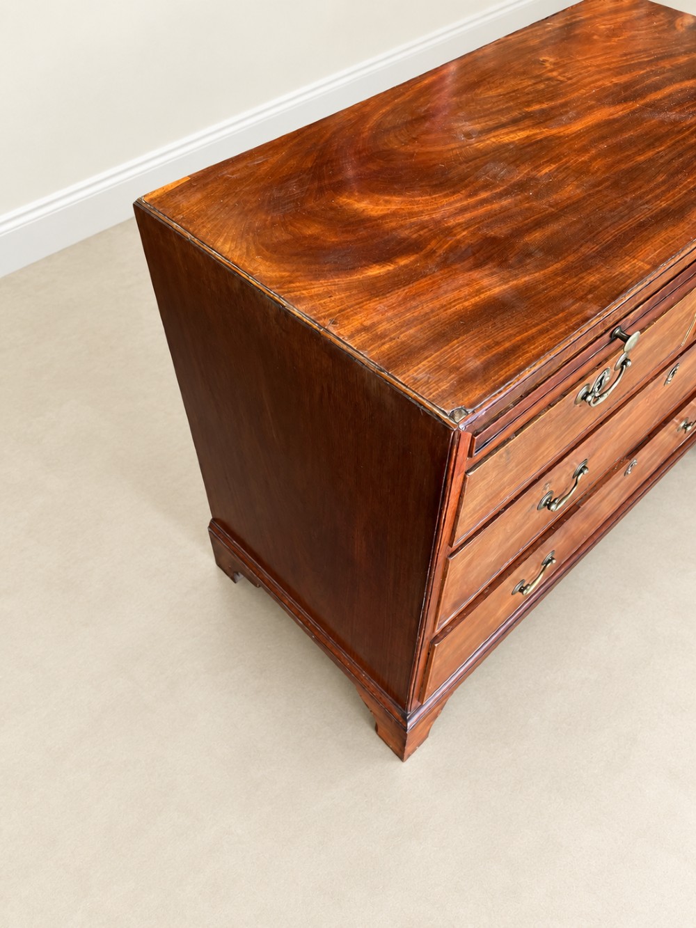 A Georgian mahogany bachelors chest featuring a brushing slide, two short over two long drawers, brass swan-neck handles, and bracket feet. View X