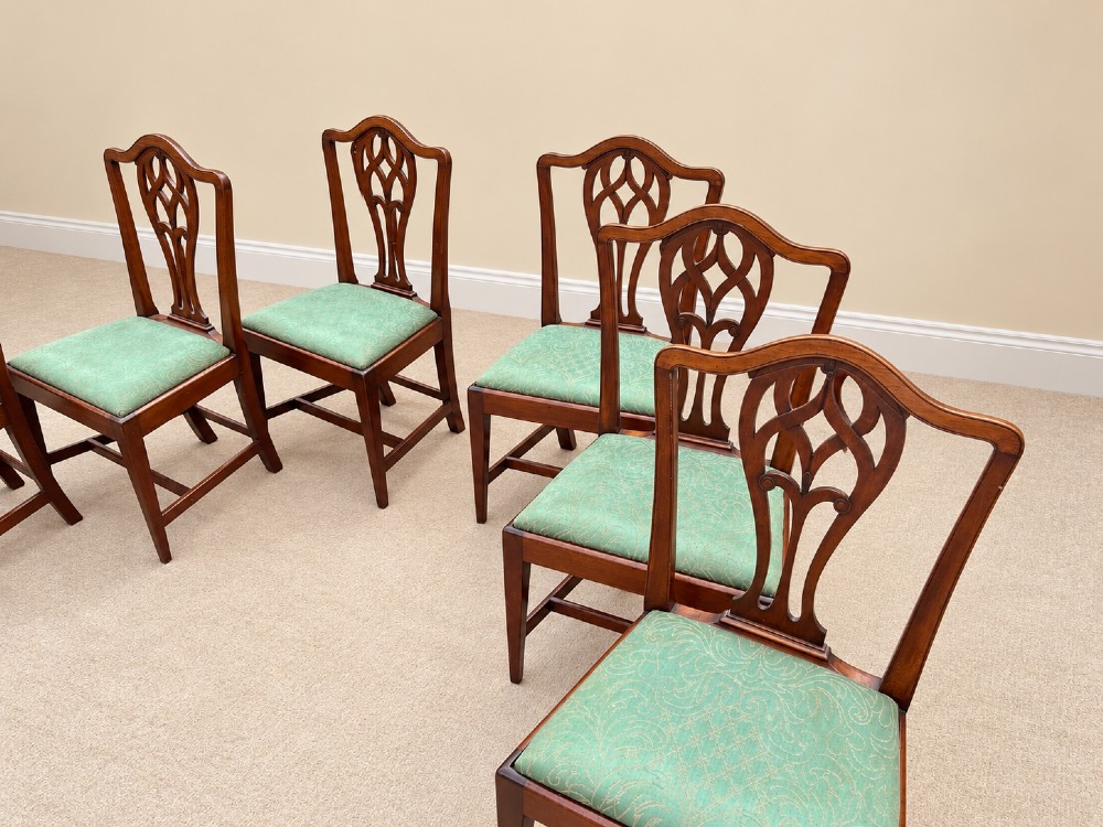 A set of six Georgian mahogany dining chairs featuring openwork pierced back splats, serpentine top rails, square legs with H-stretchers, and green patterned upholstered seats. View V