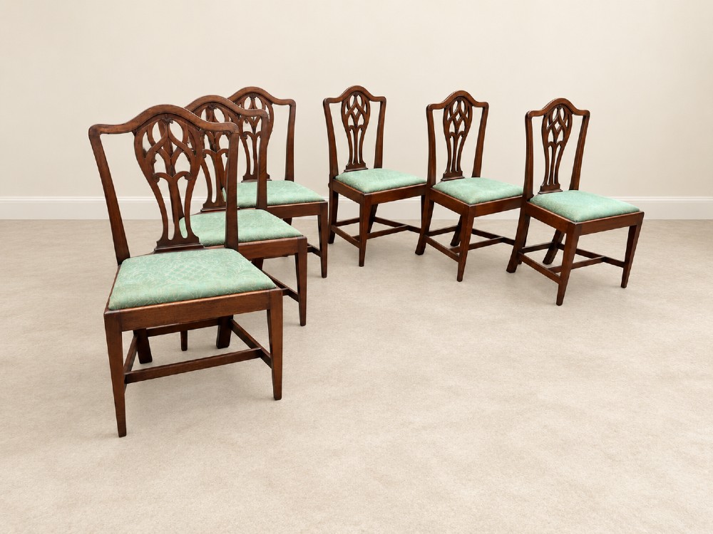 A set of six Georgian mahogany dining chairs featuring openwork pierced back splats, serpentine top rails, square legs with H-stretchers, and green patterned upholstered seats. View VI