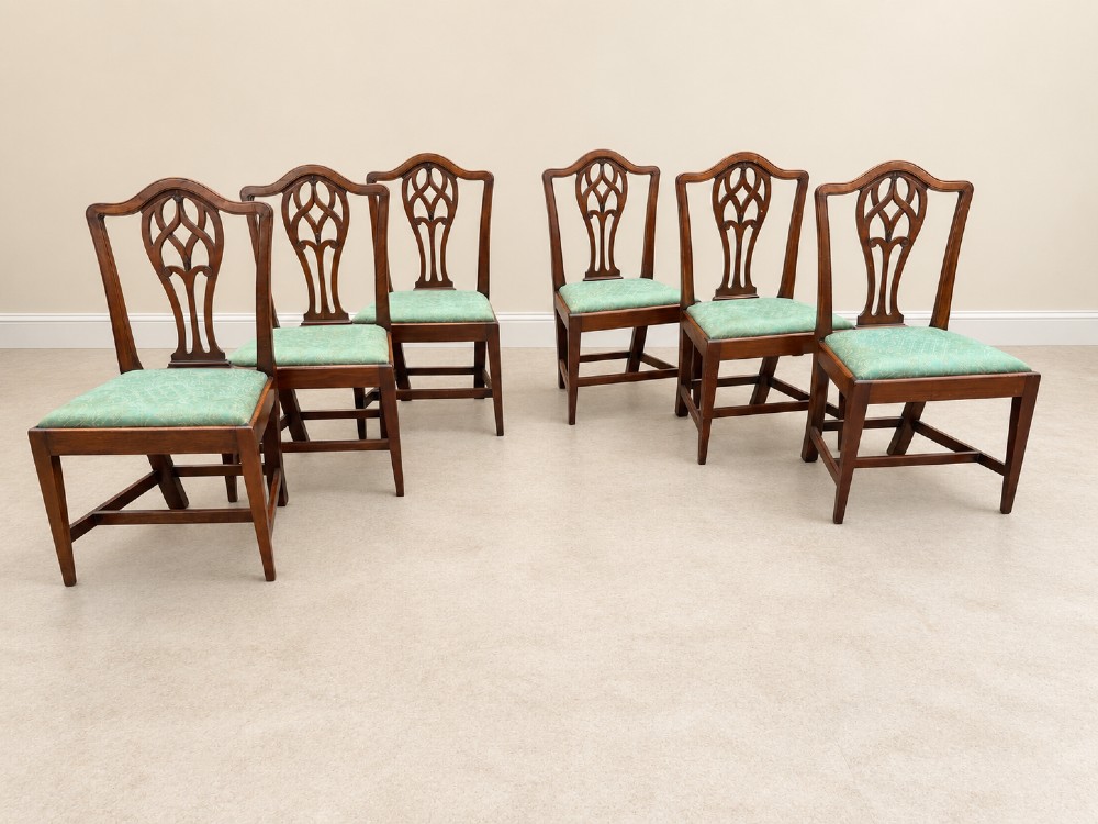 A set of six Georgian mahogany dining chairs featuring openwork pierced back splats, serpentine top rails, square legs with H-stretchers, and green patterned upholstered seats. View VII