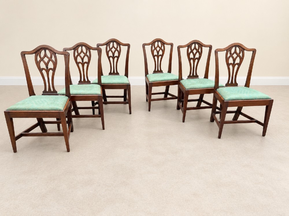 A set of six Georgian mahogany dining chairs featuring openwork pierced back splats, serpentine top rails, square legs with H-stretchers, and green patterned upholstered seats. View VIII