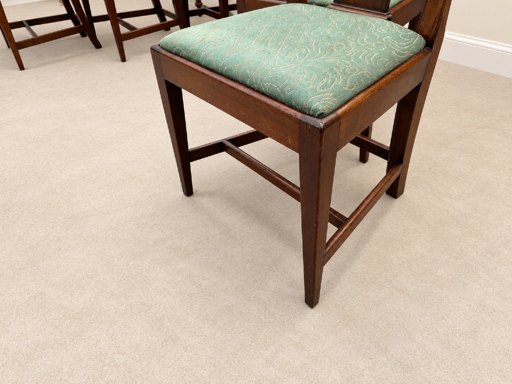 A set of six Georgian mahogany dining chairs featuring openwork pierced back splats, serpentine top rails, square legs with H-stretchers, and green patterned upholstered seats. View IX