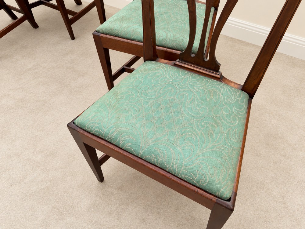 A set of six Georgian mahogany dining chairs featuring openwork pierced back splats, serpentine top rails, square legs with H-stretchers, and green patterned upholstered seats. View X