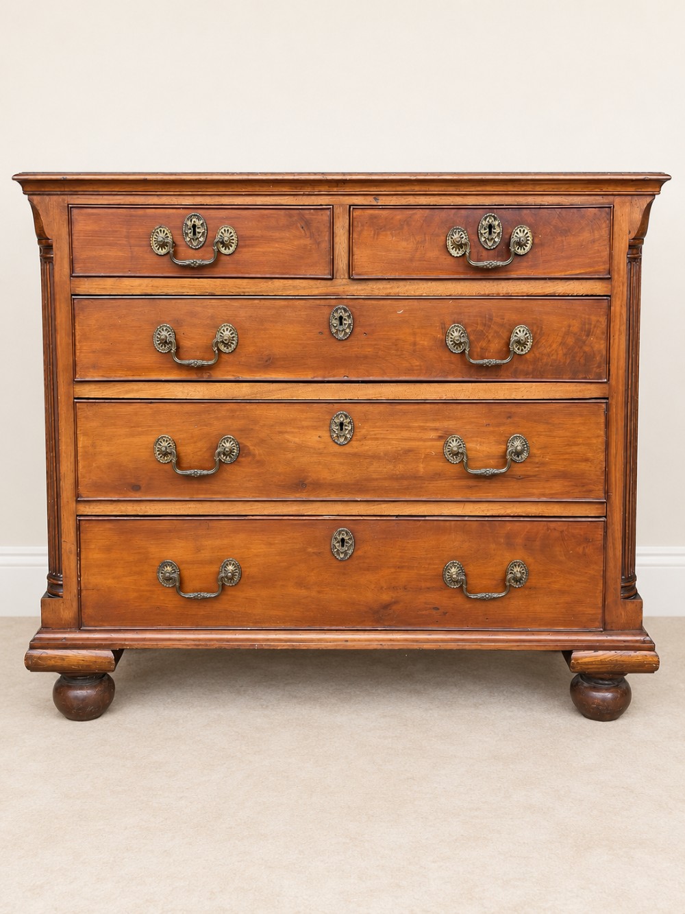 A small Georgian mahogany chest of drawers featuring two short over three long drawers with decorative brass handles, fluted quarter columns, and turned bun feet. View III
