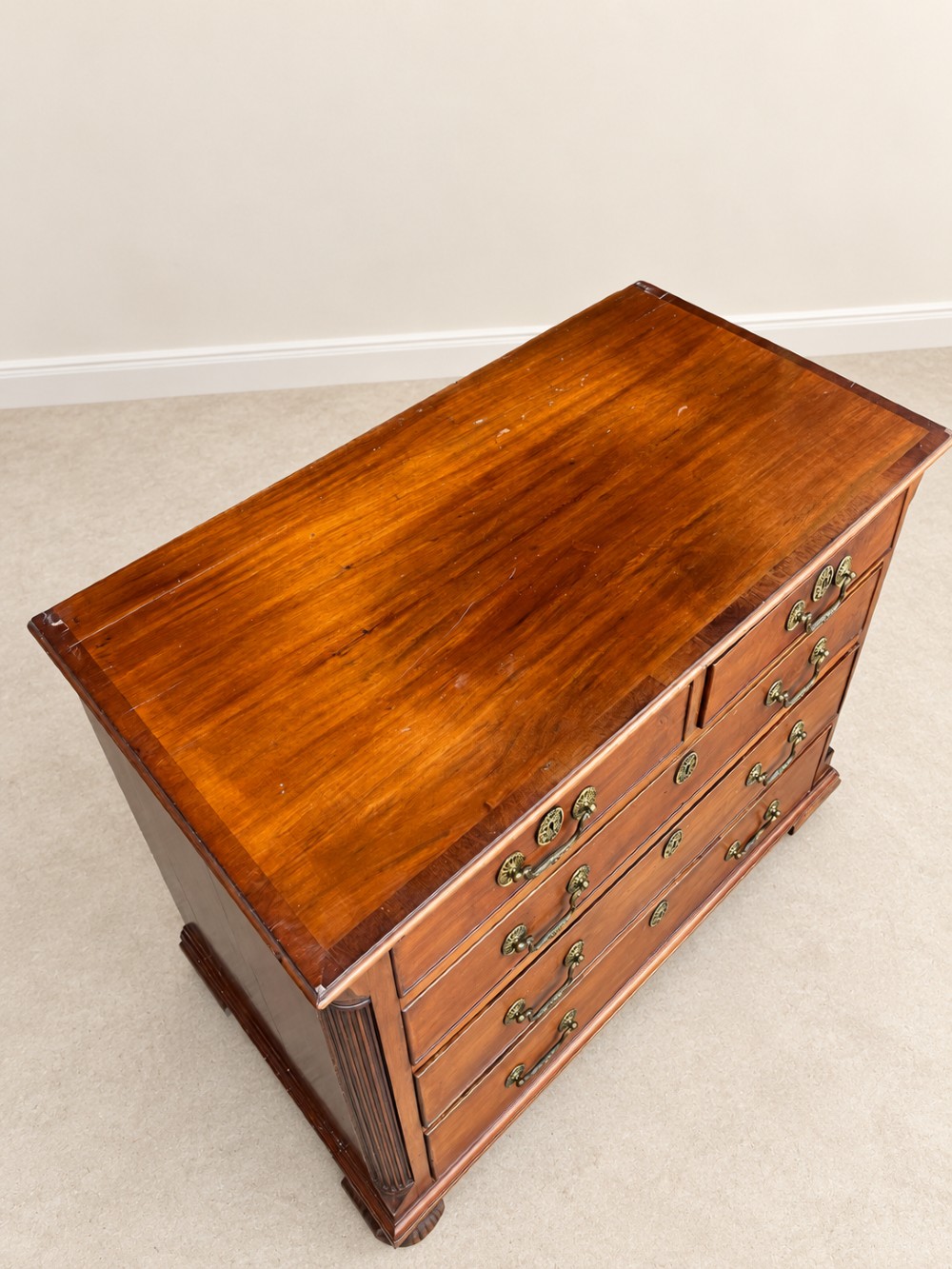A small Georgian mahogany chest of drawers featuring two short over three long drawers with decorative brass handles, fluted quarter columns, and turned bun feet. View V