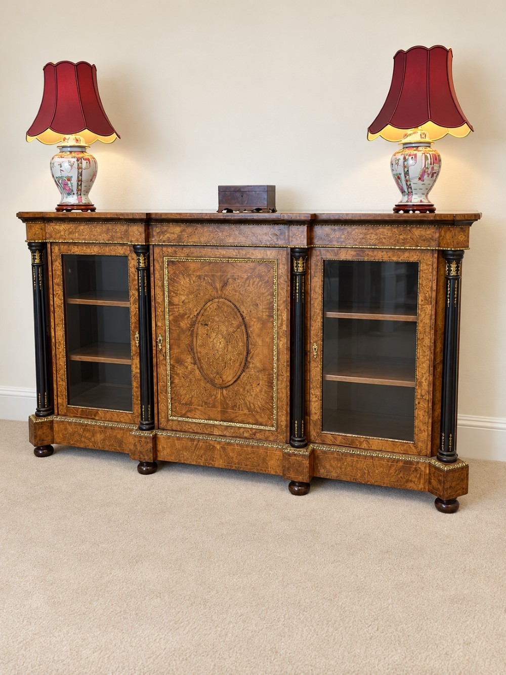 A 19th-century burr walnut credenza with a central marquetry-inlaid door flanked by two glass-front display cabinets and ebonised columns with gilt metal mounts. View IV