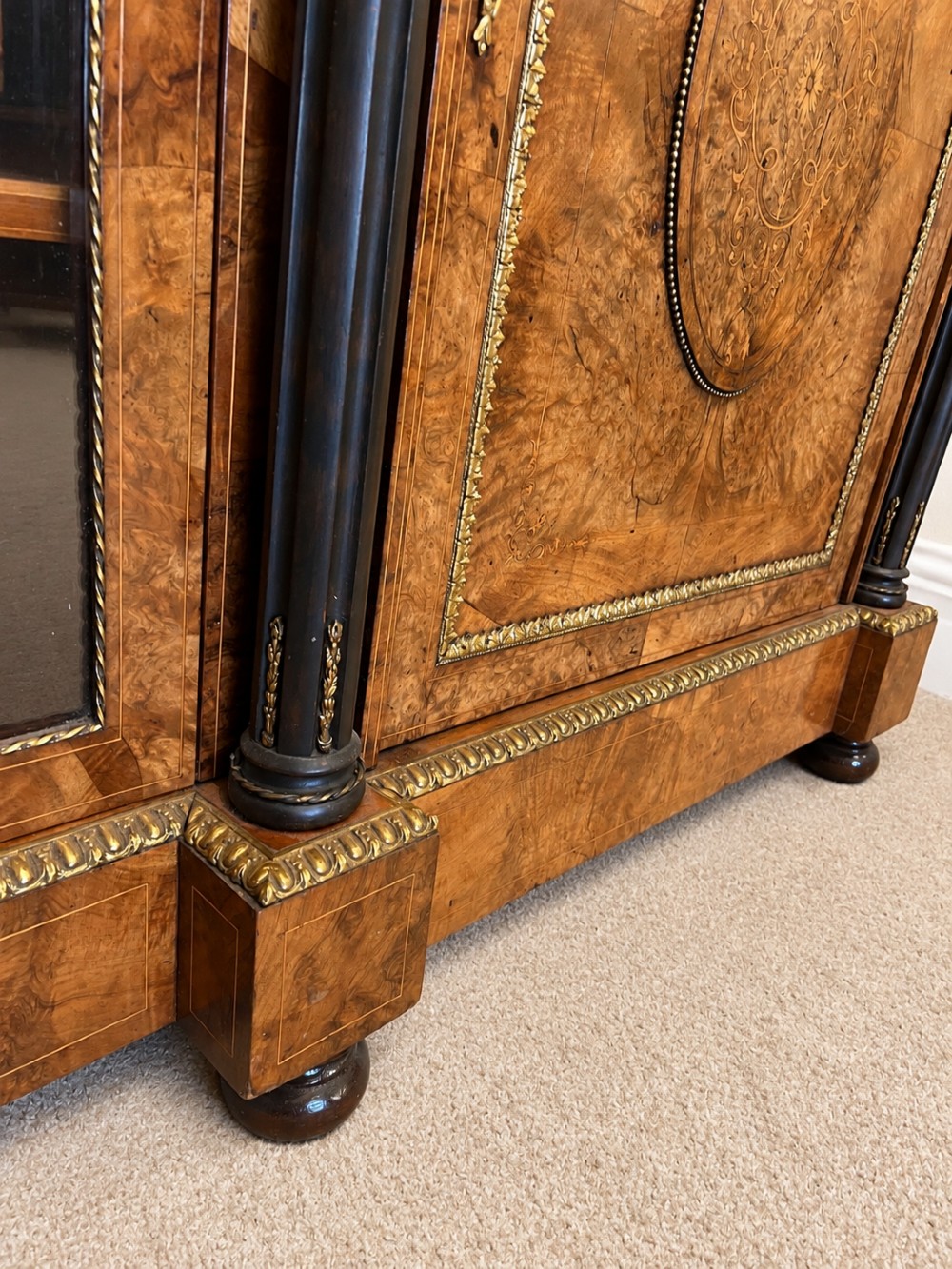 A 19th-century burr walnut credenza with a central marquetry-inlaid door flanked by two glass-front display cabinets and ebonised columns with gilt metal mounts. View X