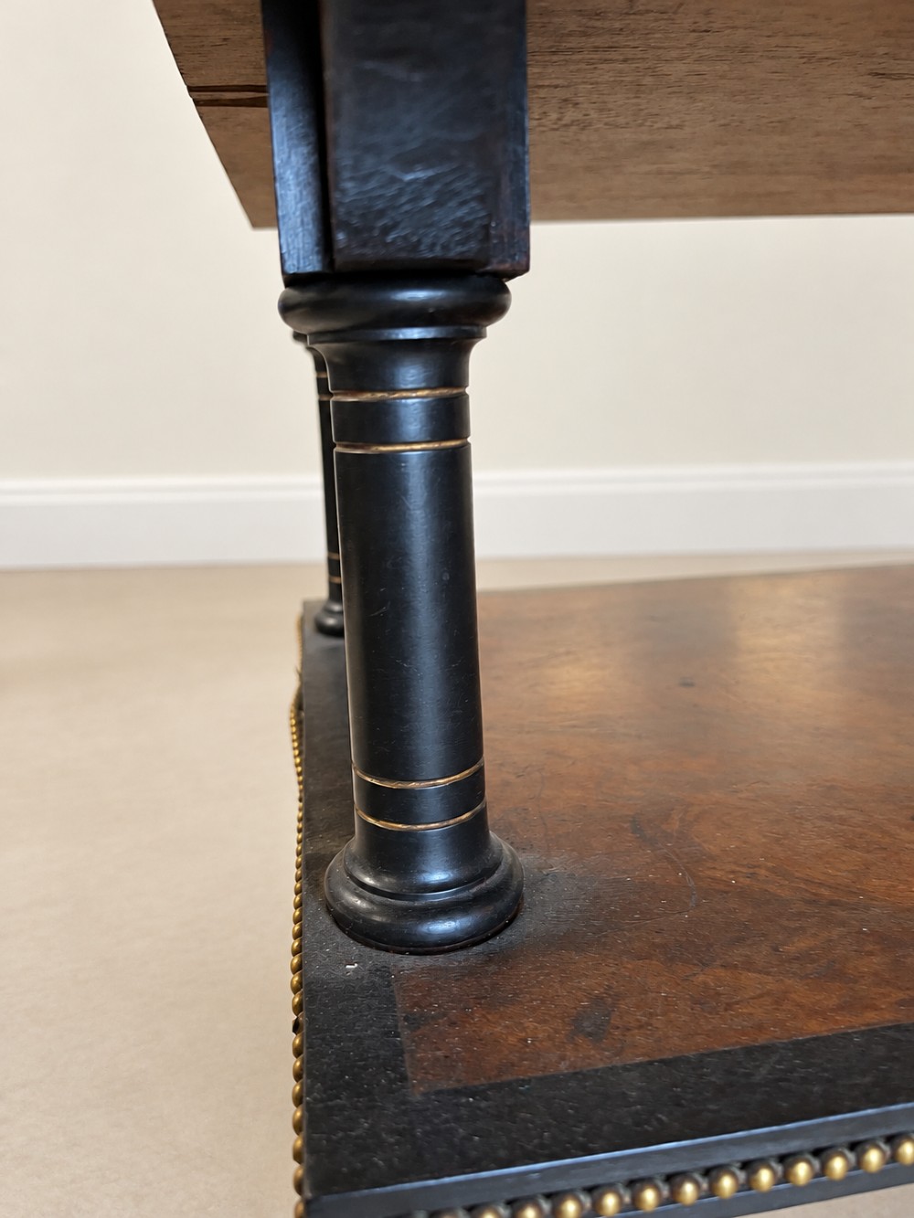 A 19th-century two-tier side table with a burr walnut surface, ebonised turned column legs, brass beaded borders, and scrolled feet on castors. View VIII