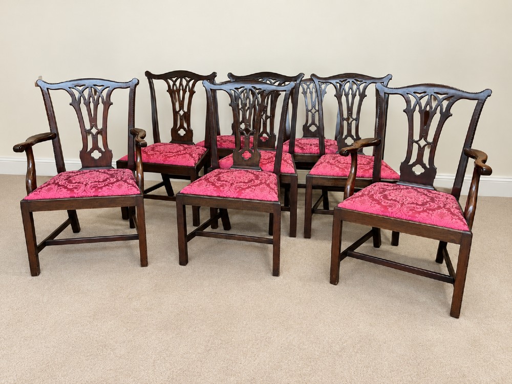 A set of eight antique Chippendale style mahogany dining chairs featuring carved pierced splats and magenta damask upholstered seats.