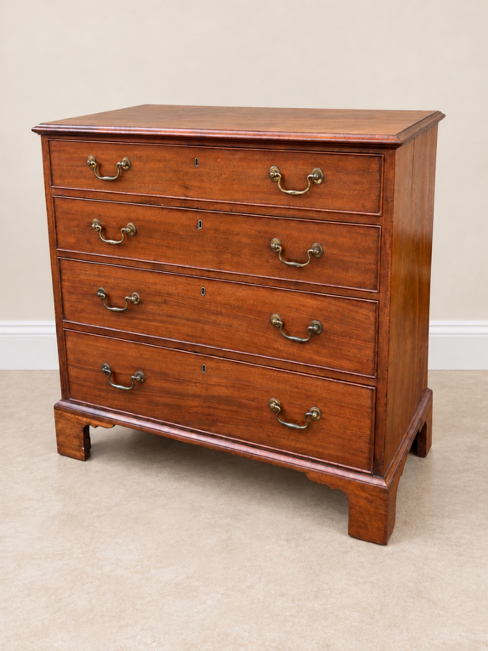 An antique Georgian mahogany chest of drawers featuring four graduated drawers with brass swan-neck handles, keyhole escutcheons, and bracket feet.