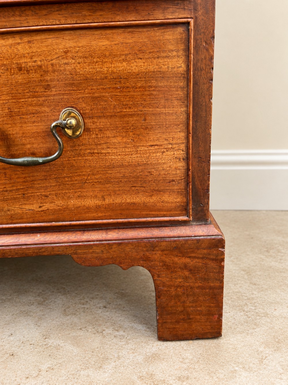 An antique Georgian mahogany chest of drawers featuring four graduated drawers with brass swan-neck handles, keyhole escutcheons, and bracket feet. View IV