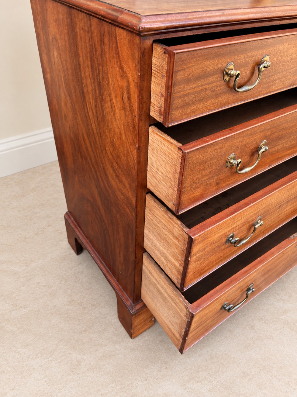 An antique Georgian mahogany chest of drawers featuring four graduated drawers with brass swan-neck handles, keyhole escutcheons, and bracket feet. View VII
