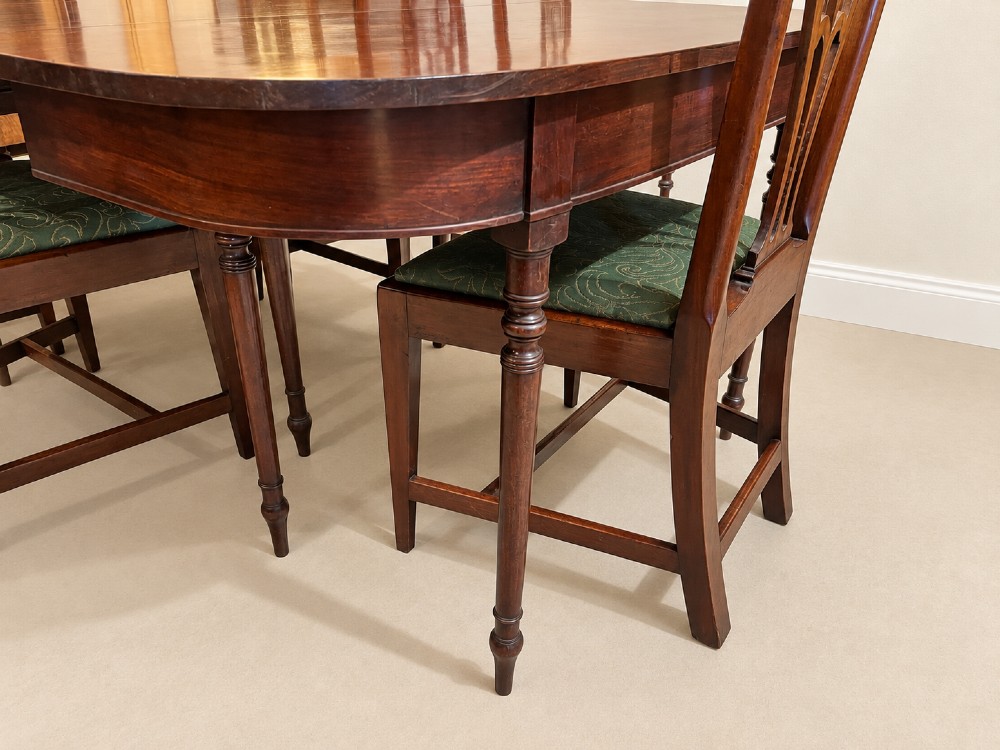 An extendable Regency mahogany dining table featuring rounded D-shaped ends, extra leaf insertions, and turned legs with brass castors. View III
