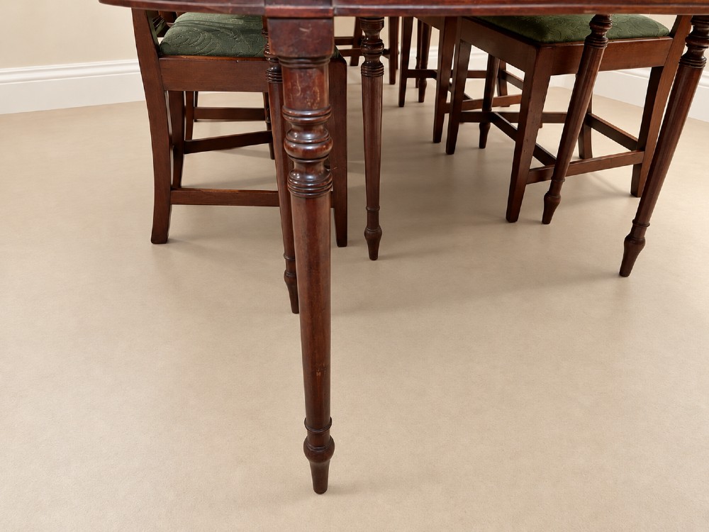 An extendable Regency mahogany dining table featuring rounded D-shaped ends, extra leaf insertions, and turned legs with brass castors. View IV